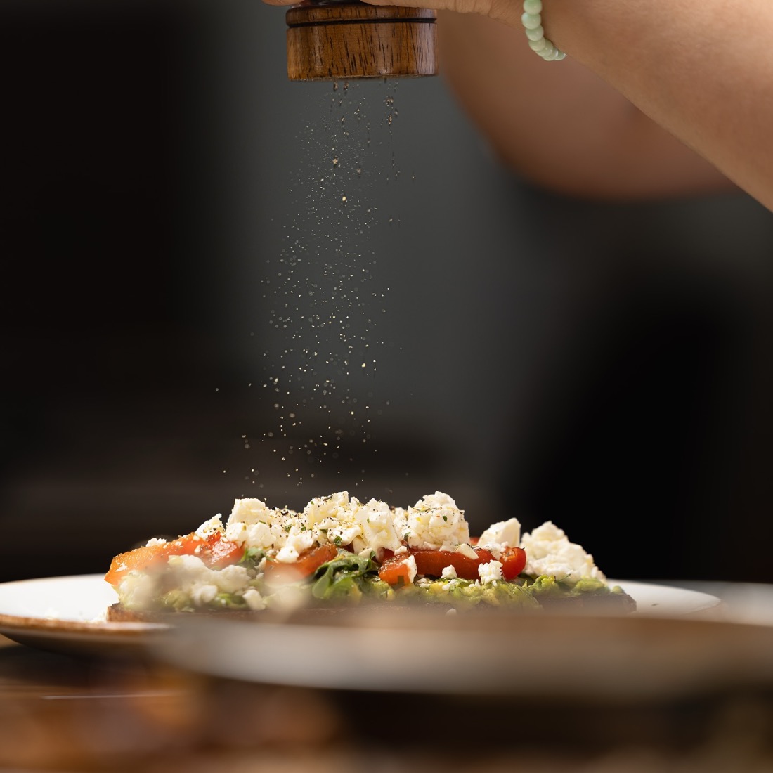 Feta being finished on avocado toast